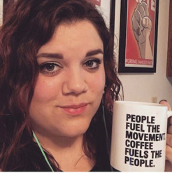 Photo of a member holding an CCI Action mug that reads 'people fuel the movement, coffee fuels the people" 