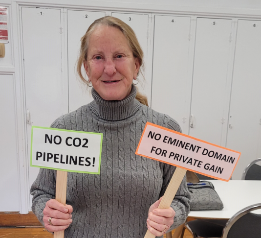 photo showing a CCI member holding signs reading "No CO2 pipelines" and "No eminent domain for private gain"